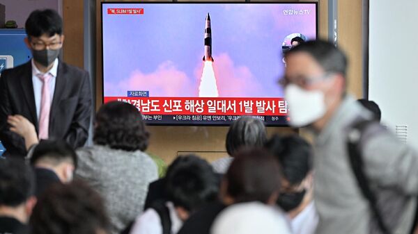 Люди возле экрана в Сеуле, транслирующего репортаж о запуске КНДР баллистической ракеты. 7 мая 2022