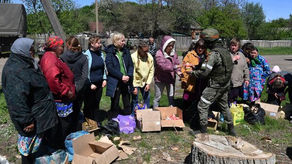 Военнослужащий ВС РФ раздает российскую гуманитарную помощь жителям одного из сел в Харьковской области