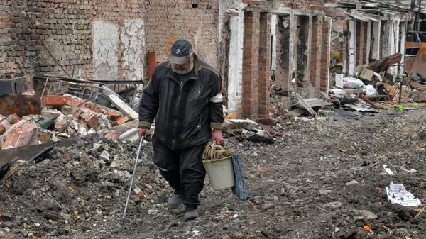 Мужчина идет мимо разрушенных построек в частном секторе города Попасная