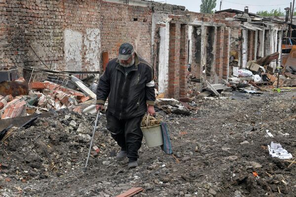 Мужчина идет мимо разрушенных построек в частном секторе города Попасная