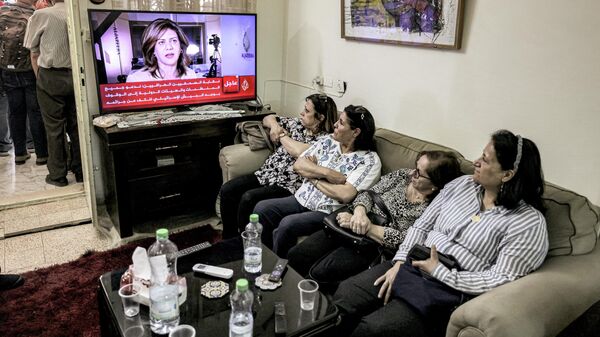 Женщины смотрят репортаж про журналистку Al Jazeera Ширин Абу Акле, погибшую при освещении столкновений на Западном берегу реки Иордан, в Восточном Иерусалиме
