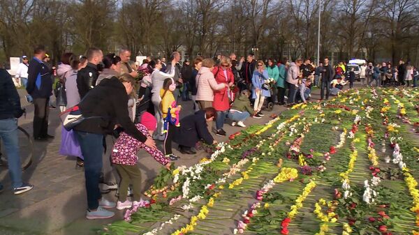 Жители Риги несут цветы к памятнику Освободителям