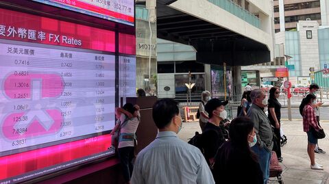 Люди проходят мимо электронного табло банка, показывающего индекс акций Гонконга, Китай