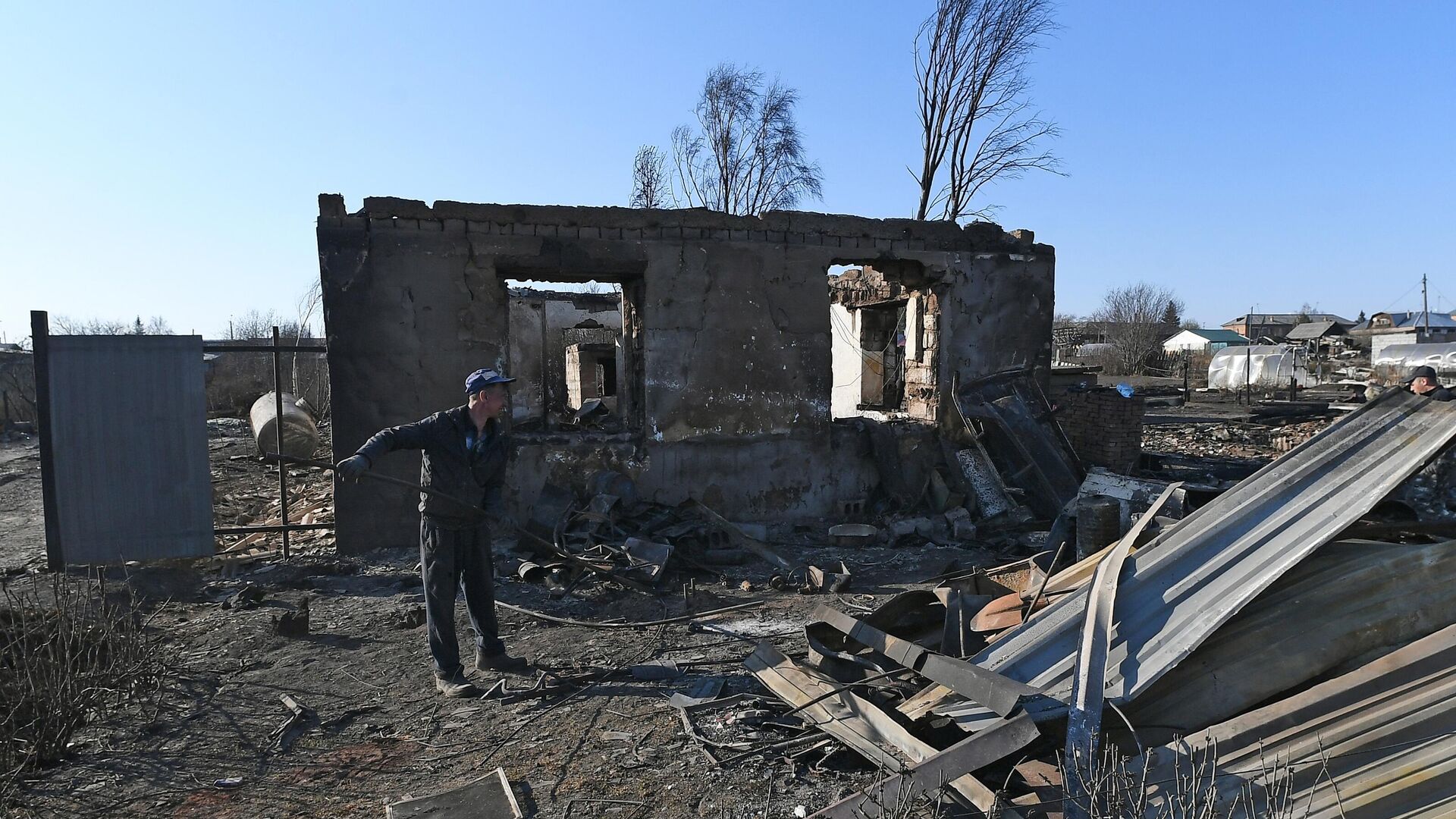 Мужчина собирает металл на пепелище сгоревшего дома для сдачи в пункт приема металлолома в городе Уяре Красноярского края - РИА Новости, 1920, 16.05.2022