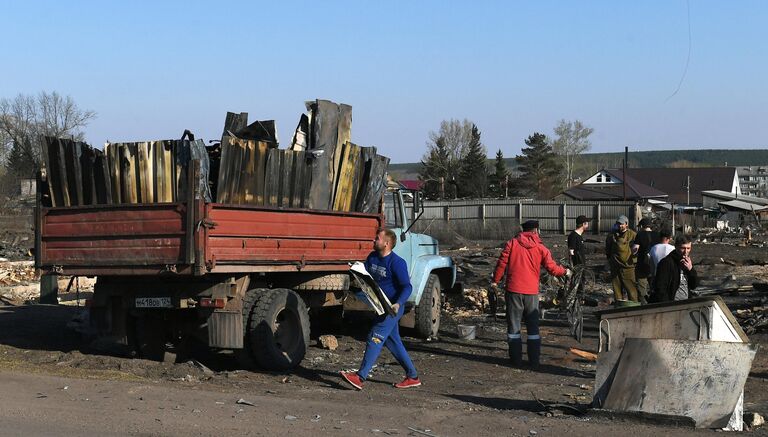 Мужчины разбирают завалы на одном из сгоревших участков в городе Уяре Красноярского края