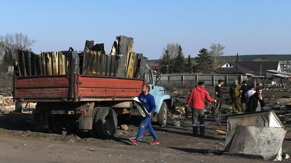 Мужчины разбирают завалы на одном из сгоревших участков в городе Уяре Красноярского края