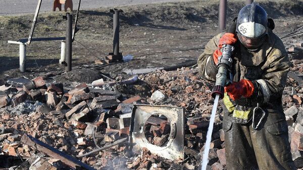 Пожарный МЧС на пепелище сгоревшего дома в городе Уяре Красноярского края