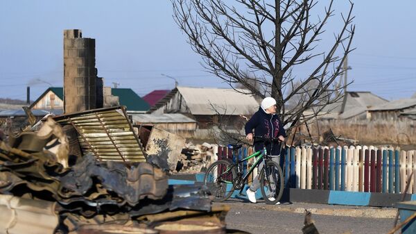 Женщина возле сгоревшего дома в городе Уяре Красноярского края