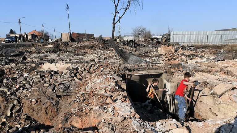 Дети разбирают завал в подвале сгоревшего дома в городе Уяре Красноярского края