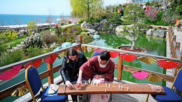 Девушки играют на японском щипковом музыкальном инструменте Кото в японском саду Шесть чувств на территории Mriya Resort & SPA в Крыму