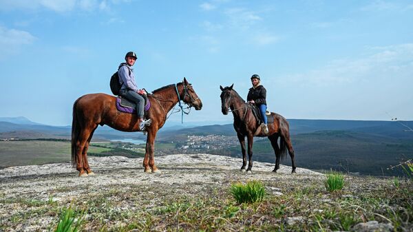 Молодые люди катаются верхом на лошадях по горному маршруту в районе Партизанского водохранилища в Крыму