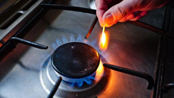 Женщина зажигает горелку газовой плиты
