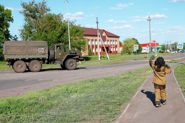 Восьмилетний мальчик Алеша приветствует проезжающие мимо российские военные автомобили в селе Веселая Лопань в Белгородской области