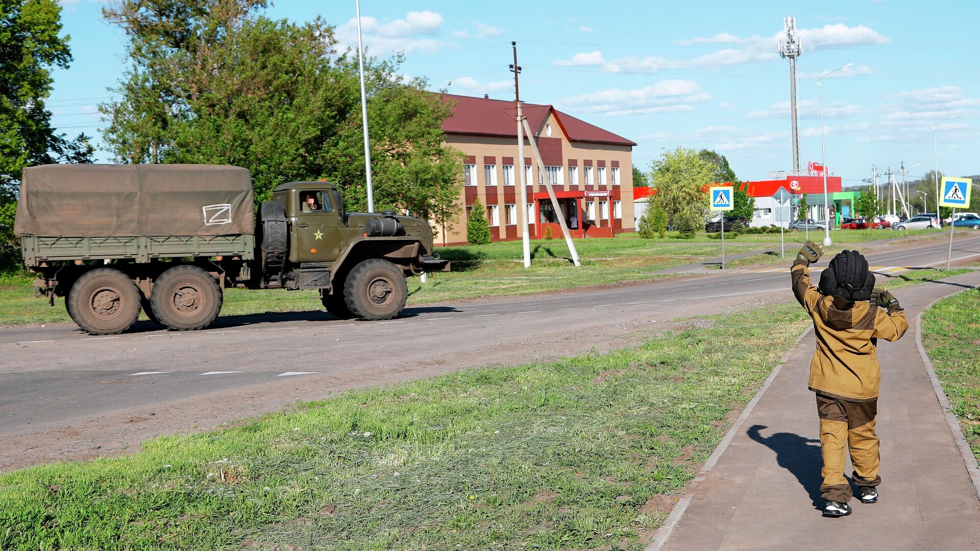 Восьмилетний мальчик Алеша приветствует проезжающие мимо российские военные автомобили в Белгородской области - РИА Новости, 1920, 17.05.2022