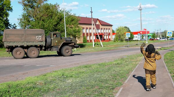 Восьмилетний мальчик Алеша приветствует проезжающие мимо российские военные автомобили в Белгородской области