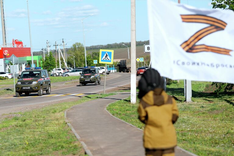 Восьмилетний мальчик Алеша приветствует проезжающие мимо российские военные автомобили в селе Веселая Лопань в Белгородской области