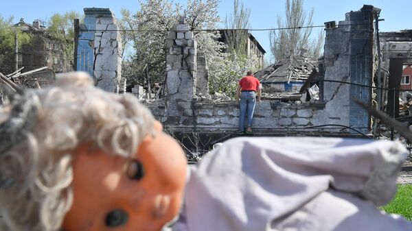Житель Мариуполя осматривает место своего разрушенного дома в Левобережном районе
