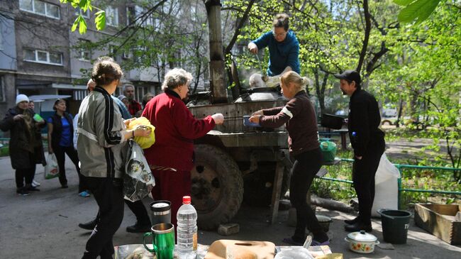 Жители готовят еду в полевой кухне во дворе разрушенного дома в Левобережном районе Мариуполя