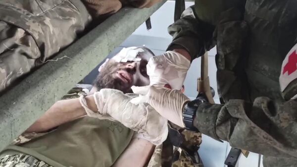 Медик оказывает помощь одному из раненых украинских военных с Азовстали в Мариуполе, сдавшихся в плен