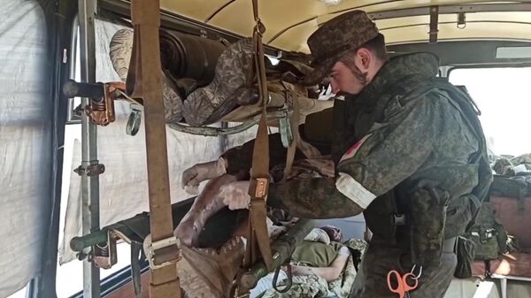 Медик оказывает помощь раненому украинскому военному с Азовстали в Мариуполе, сдавшемуся в плен