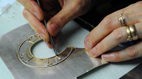 Ювелир - филигранщик ЗАО Фабрика Ростовская финифть работает с серебряной нитью при создании орнамента на окладе