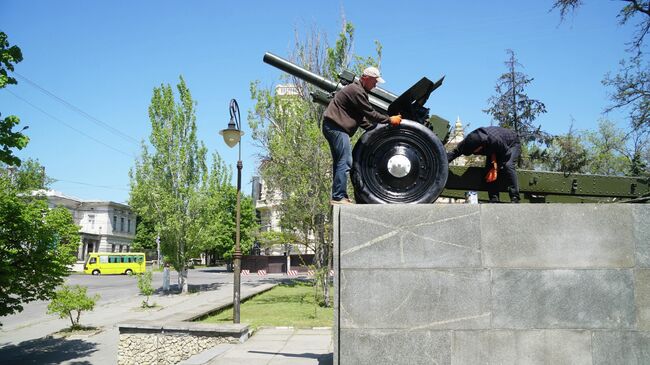 Мужчины красят пушку на постаменте в Херсоне