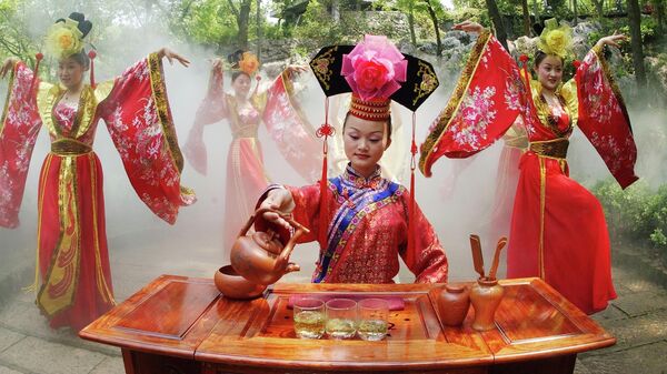 Актриса в традиционной китайской одежде выступает на чайной церемонии в чайном саду Лунцзиншань в Ханчжоу, Китай