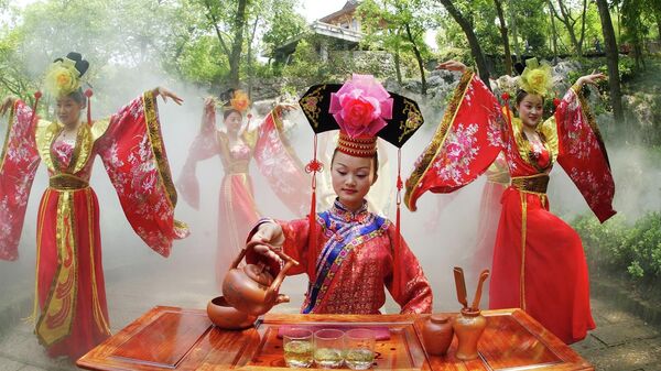 Актриса в традиционной китайской одежде выступает на чайной церемонии в чайном саду Лунцзиншань в Ханчжоу, Китай