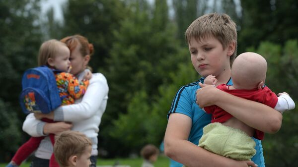  Беженцы с детьми из города Славянск перед отправкой на автобусах из пригорода Донецка на территорию России
