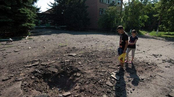 Местные жители у воронки от снаряда, разорвавшегося рядом с одной из школ в Краматорске, 2014 год.
