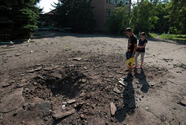 Местные жители у воронки от снаряда, разорвавшегося рядом с одной из школ в Краматорске, 2014 год.
