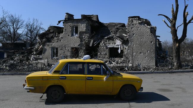 Автомобиль проезжает мимо разрушенного дома в Волновахе