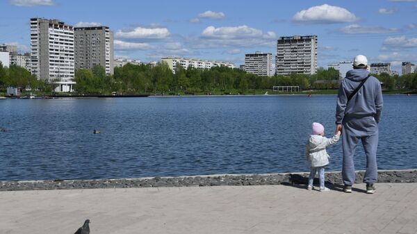 Мужчина с ребенком возле Гольяновского пруда на территории парка в Москве