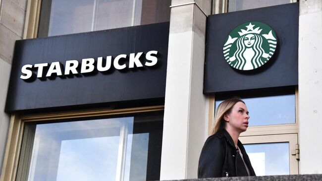 Девушка проходит мимо кофейни Starbucks в Москве