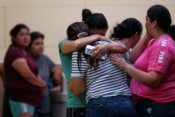 Люди плачут после массовой стрельбы в начальной школе в городе Ювалде, штат Техас