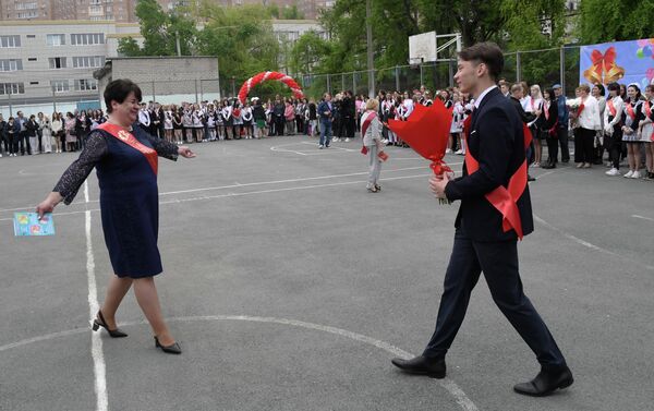 Выпускник дарит цветы учителю во время последнего звонка в гимназии №2 во Владивостоке
