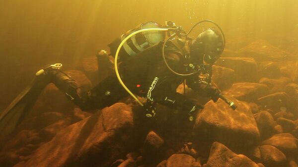 Участник проекта 1XPEDITION Андрей Петров обследует основание старинной пристани, найденной в акватории острова Святой, при помощи подводного металлоискателя