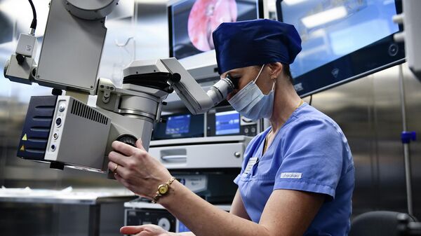 Хирургическая сестра демонстрирует работу микроскопа в операционном блоке 