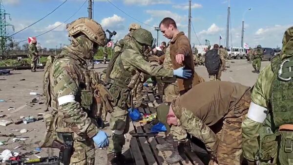 Российские военнослужащие досматривают сдавшихся в плен украинских военнослужащих и боевиков националистического батальона Азов на территории комбината Азовсталь