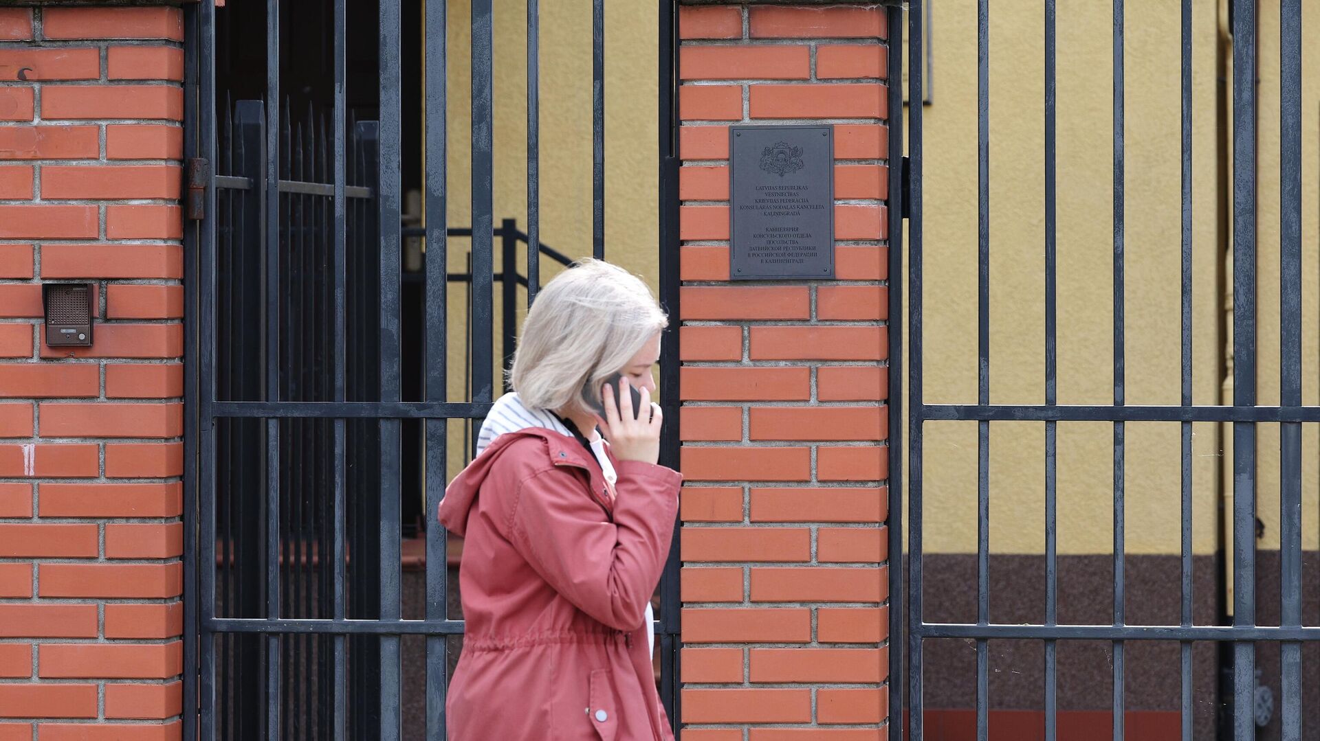 Девушка проходит рядом с воротами канцелярии консульского отдела посольства Латвии в Калининграде - РИА Новости, 1920, 27.05.2022