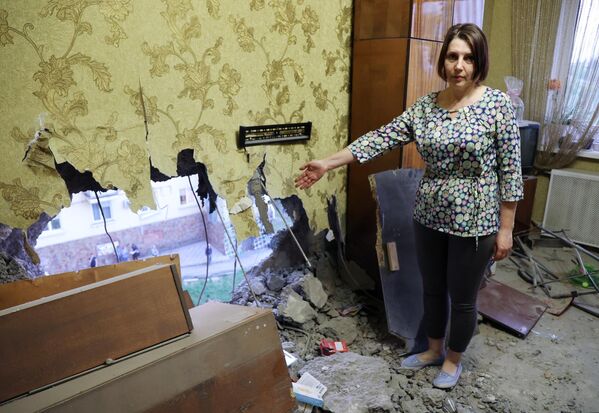Женщина показывает отверстие в стене после обстрела ВСУ жилого сектора в Буденновском районе Донецка