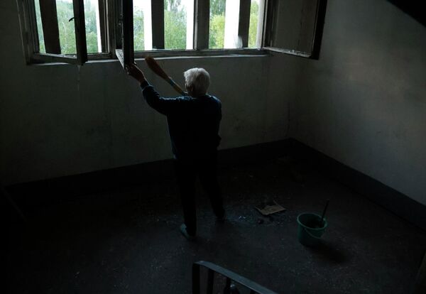 Женщина убирает осколки стекол на лестнице в подъезде жилого дома после обстрела ВСУ жилого сектора в Буденновском районе Донецка