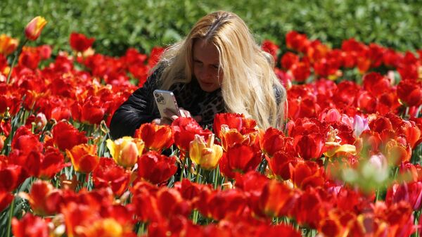 Женщина фотографирует цветы в Парке Горького в Москве