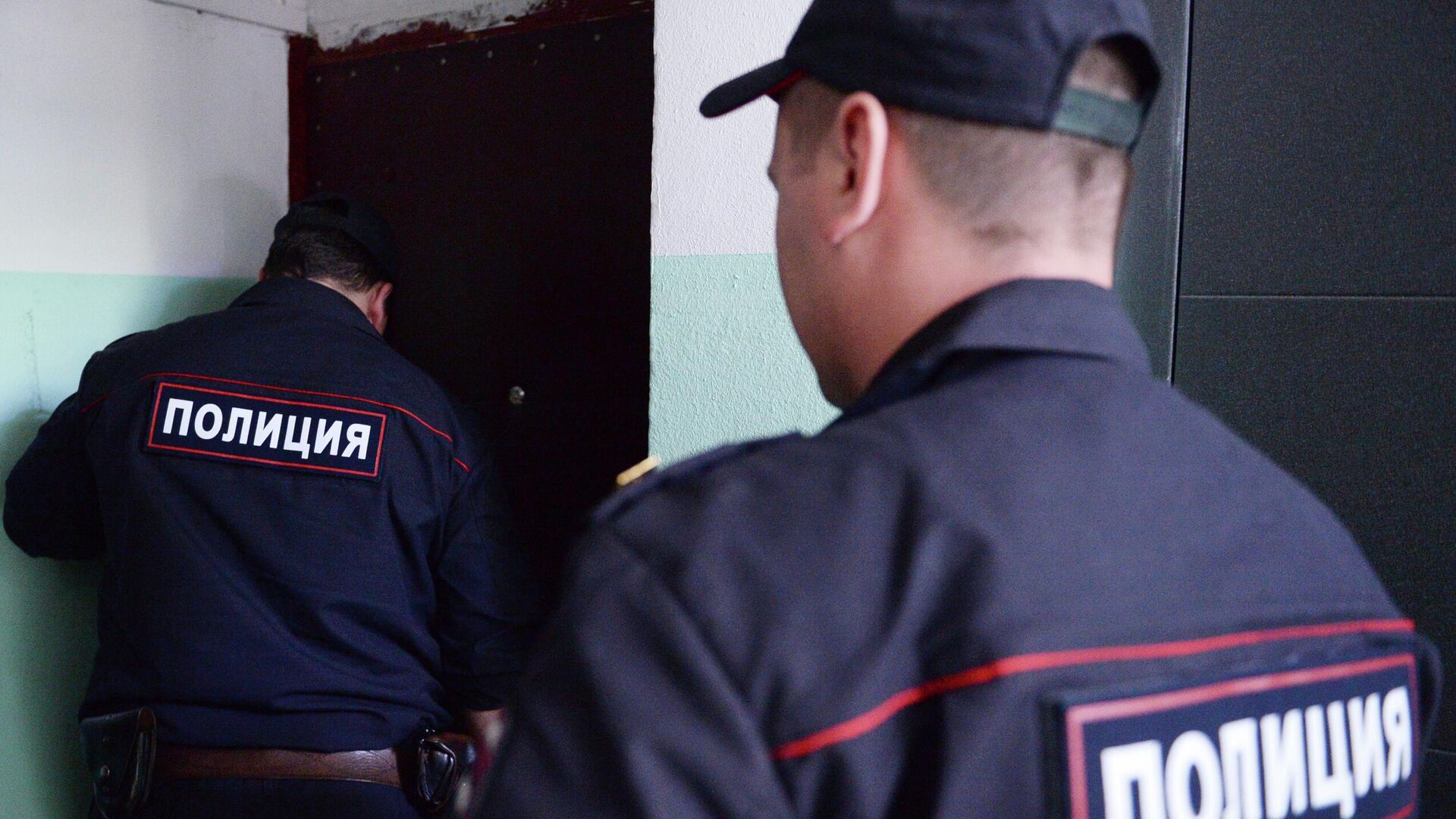 Сотрудники полиции стоят у двери квартиры - РИА Новости, 1920, 06.07.2022