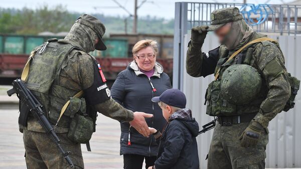 Военнослужащие угощают конфетами ребенка на одной из улиц в городе Купянск