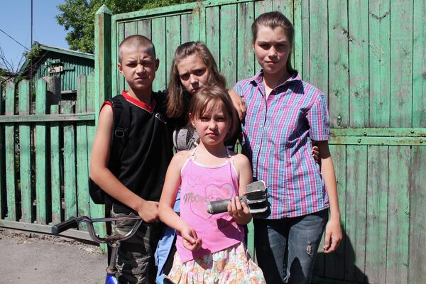 Дети показывают фрагмент снаряда, попавшего в дом в результате обстрела украинскими силовиками в Донецке.