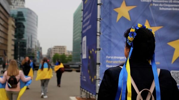 Протестующие несут украинские флаги, принимая участие в демонстрации возле штаб-квартиры ЕС в Брюсселе