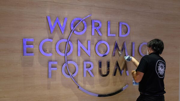 Рабочий чистит вывеску с логотипом Всемирного экономического форума в Давосе. 22 мая 2022 года