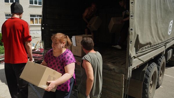 Местные жители разгружают коробки с гуманитарной помощью в пункте распределения помощи в Рубежном