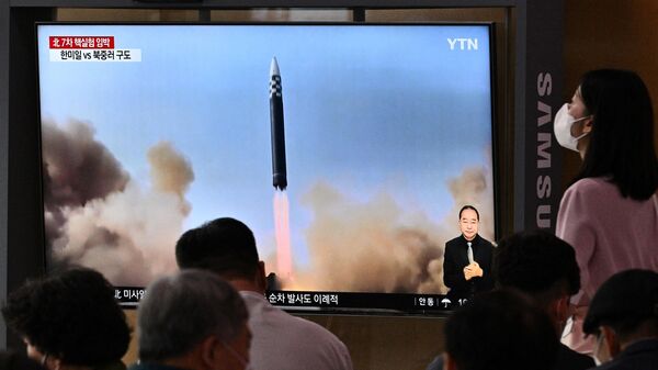 Люди возле экрана в Сеуле, транслирующего репортаж о запуске КНДР баллистической ракеты. 5 июня 2022